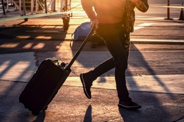 man walking with his black luggage bag