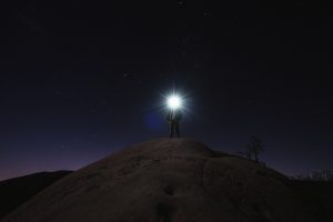 man standing on mountain white holding flashlight